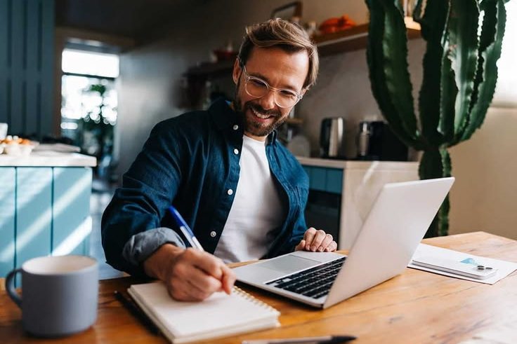 Man planning his debt payoff with a notebook and laptop