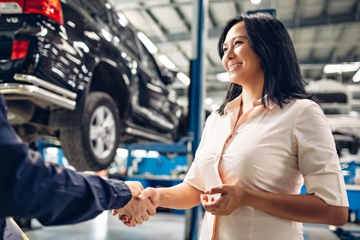 Woman shaking hands with a mechanic after an urgent car repair