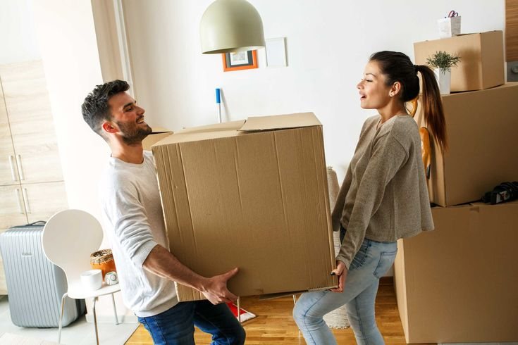 Couple carrying moving boxes into their new home